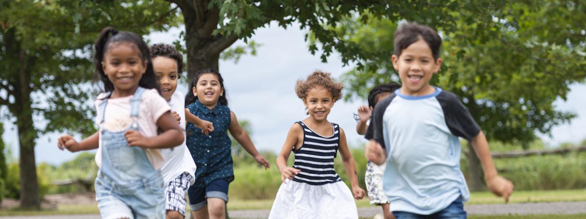 Phot of 6 diverse children smiling and running toward camera
