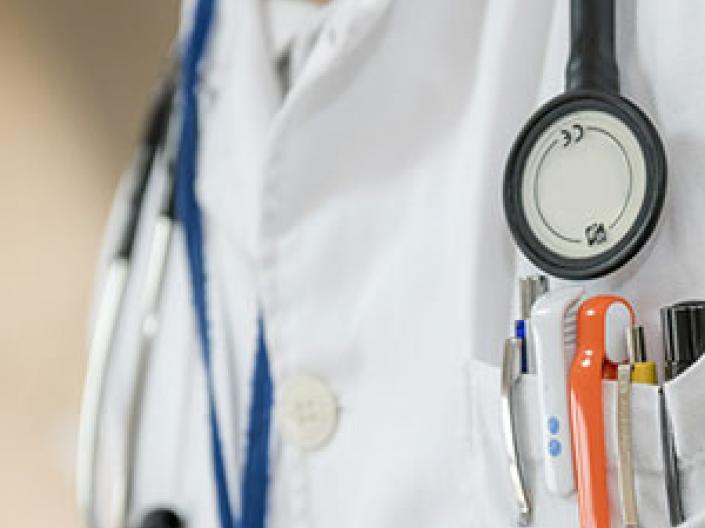 Closeup of a doctor's chest with a stethoscope and pens