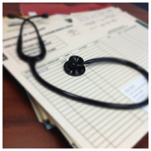 A stethoscope lying on patient records