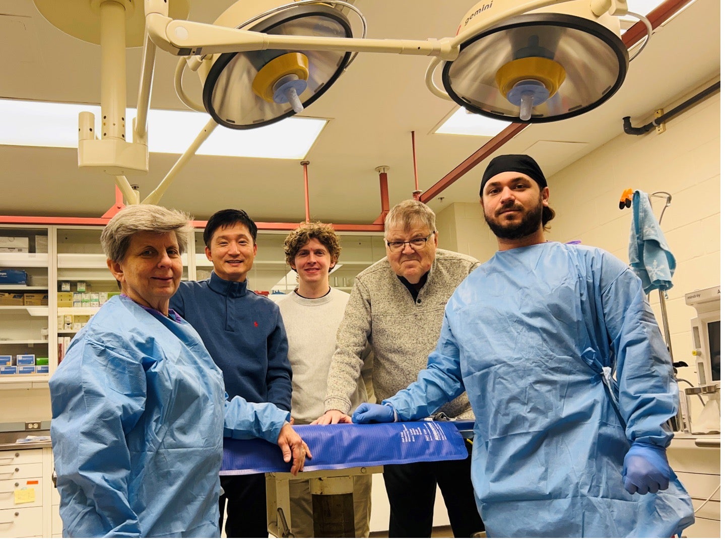 Researchers from Dr. Seungyup Lee's lab gather in a medical room to pose for a group photo.