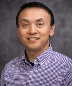 Headshot of Youwei Zhang with blue checkered collared shirt and grey blurred background