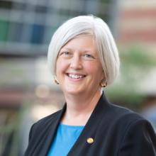 Photo of Jen Brull, a female with white hair and wearing a black jacket