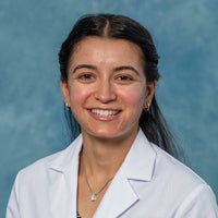 Woman with long dark hair in white coat