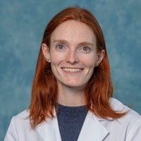 Woman with long red hair in a white coat