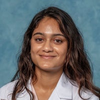 Woman with long dark hair in white coat