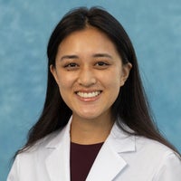 Woman with long dark hair in white coat