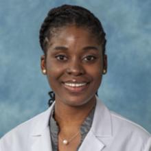 woman with dark hair and a white coat