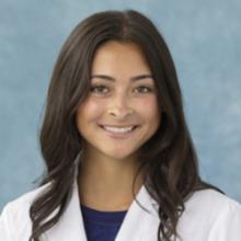 woman with long dark hair and a white coat