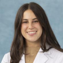 woman with long dark hair and a white coat