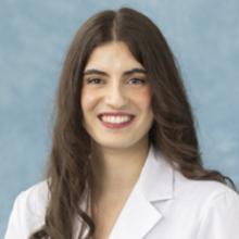 woman with long dark hair and a white coat
