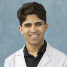 man with short, dark hair and a white coat