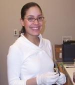 Marjorie in the lab with white gloves on smiling.