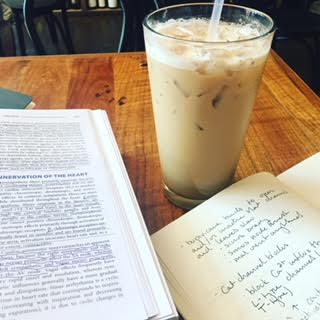 Book, coffee, and notebook on table