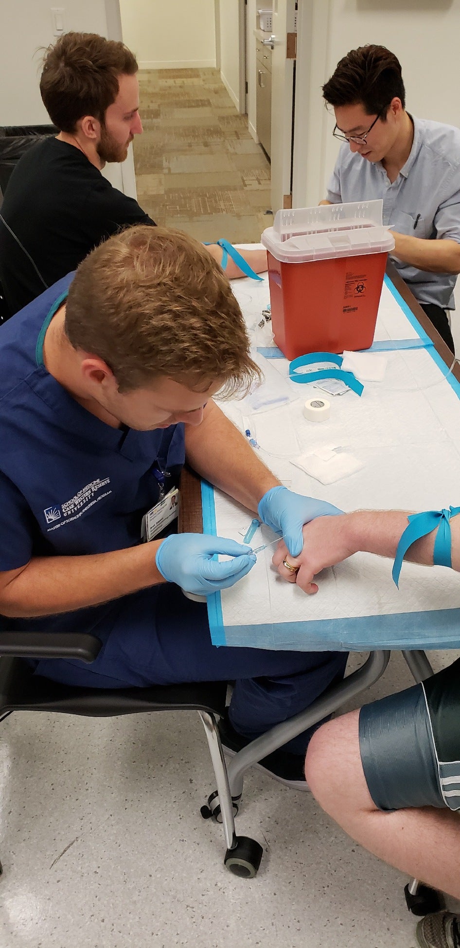 CWRU MSA student practicing IV on hand with two students in background