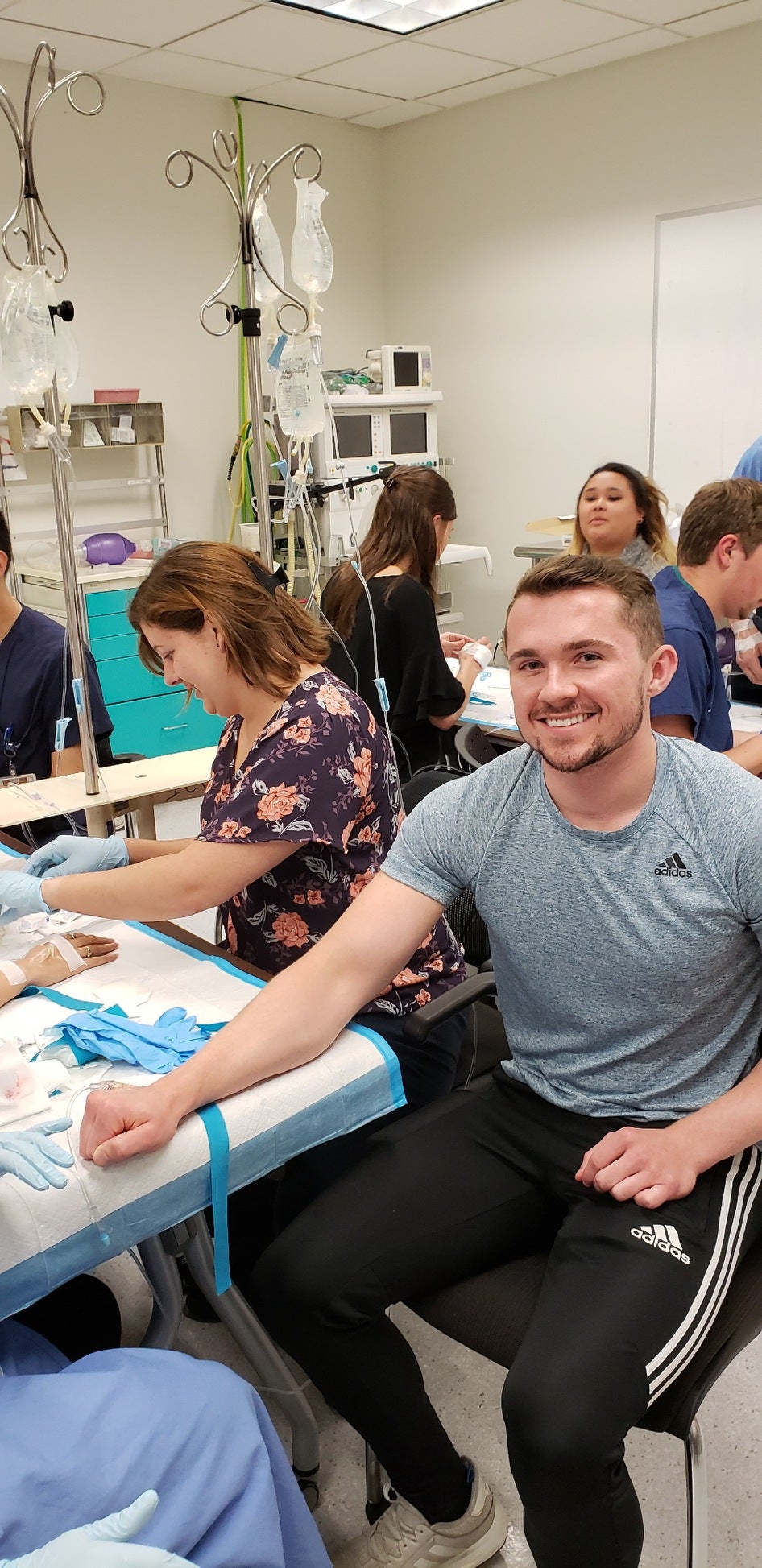 CWRU MSA student smiling at camera while waiting for peer to practice IV
