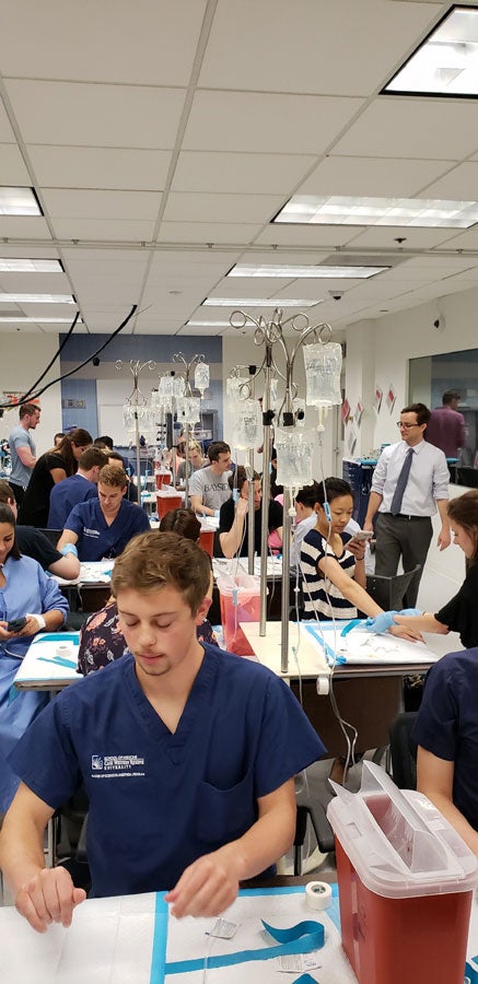 Male certified anesthesiologist assistant student in front of classroom with IV kit