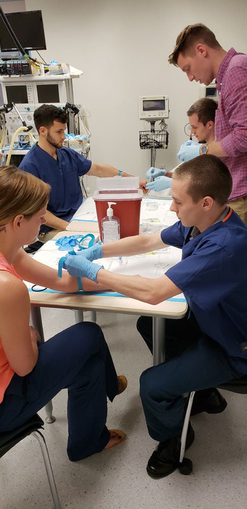 Five master of science in anesthesia students preparing and practicing IVs