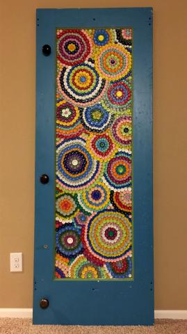 Artwork of colorful circles made partially from recycled caps and set in a door