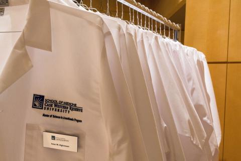 White coats on rack with CWRU MSA logo and name tag