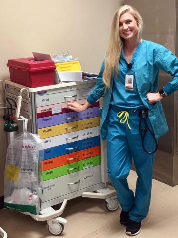 Female certified anesthesiologist assistant student standing in front of medical cart
