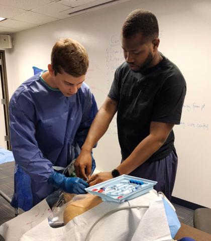 Male Master of Science in Anesthesia student and male certified anesthesiologist assistant practice IV on mannequin