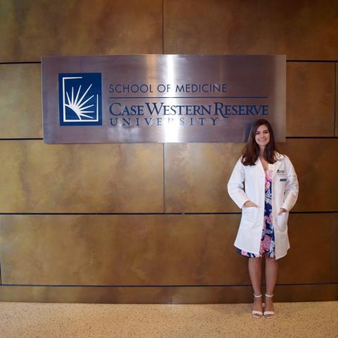Female anesthesiologist assistant student standing with sign reading, School of Medicine Case Western Reserve University