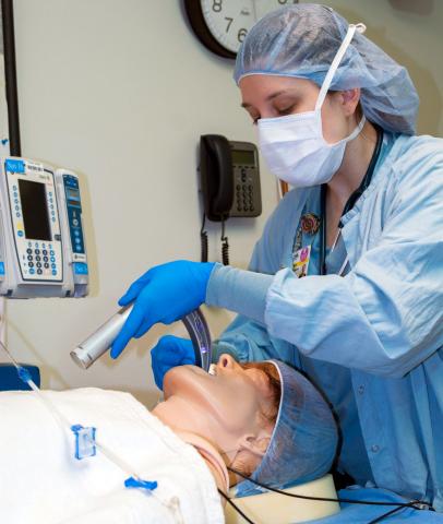 Female student intubating mannequin in simulation lab
