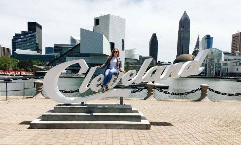 Female masters student sitting on Cleveland sign in Cleveland, Ohio