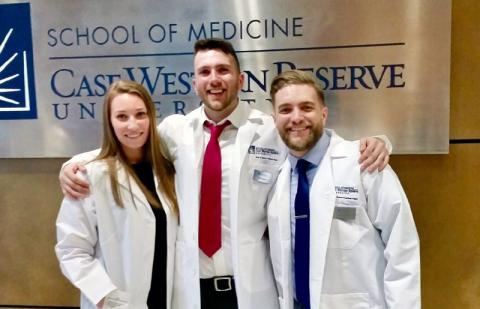 Three anesthesiologist assistant students in white coats in front of CWRU School of Medicine sign