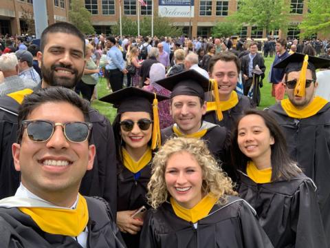 Eight anesthesiologist assistant graduates posing in caps and gowns