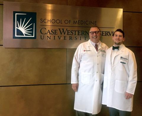 Two male certified anesthesiologist assistants in front of Case Western Reserve University School of Medicine sign