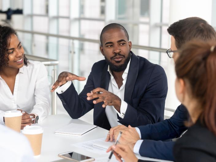 Group of people conversing at table with notepads