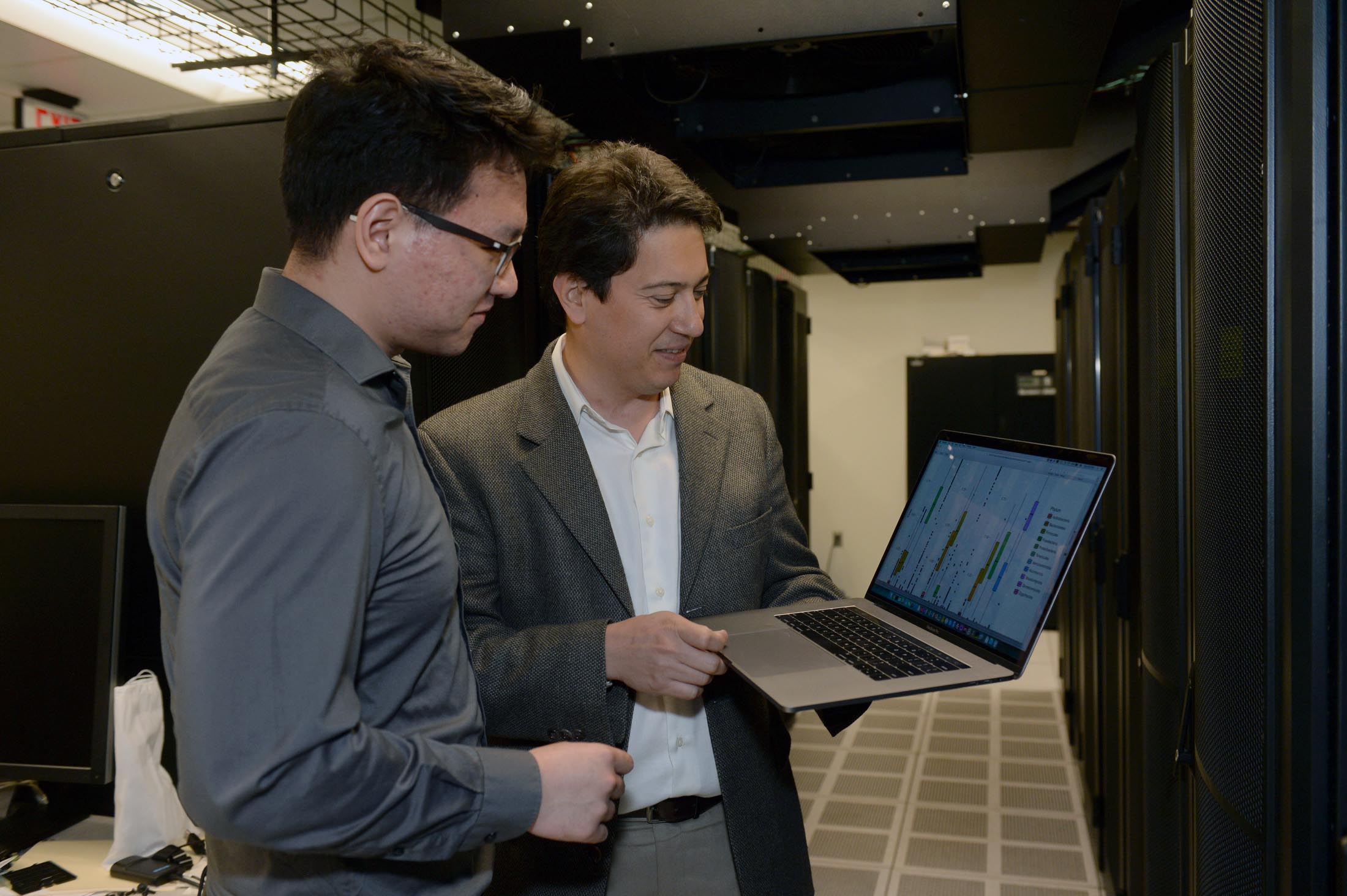 A professor and a student look at data together on a laptop.