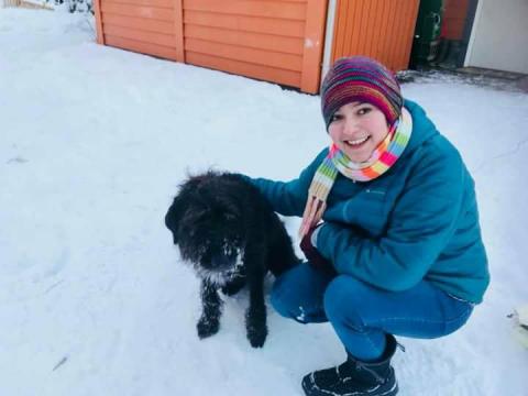 Photo of Fabiana Irigoyen playing with a black dog in the snow.