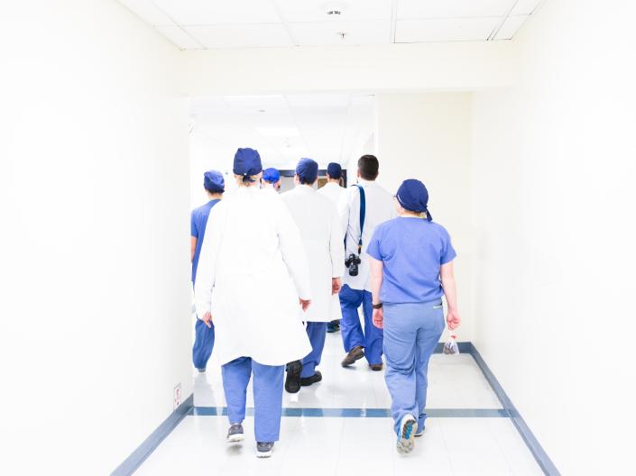 A group of healthcare professionals in scrubs walk down a hospital hall.