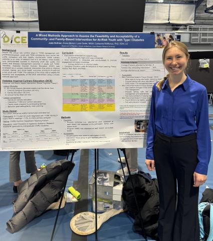 Jade Dohner stands to the right of a large research poster on an easel.