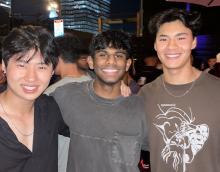 Three men stand with arms over each other's shoulders.  Isaac Alexander is in the middle.