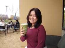 Emily Cheng wearing a red sweater and holding a cup of coffee.