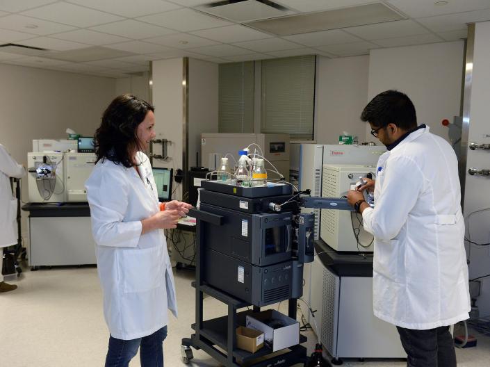 Two researchers wearing white lab coats prepare samples for analysis.