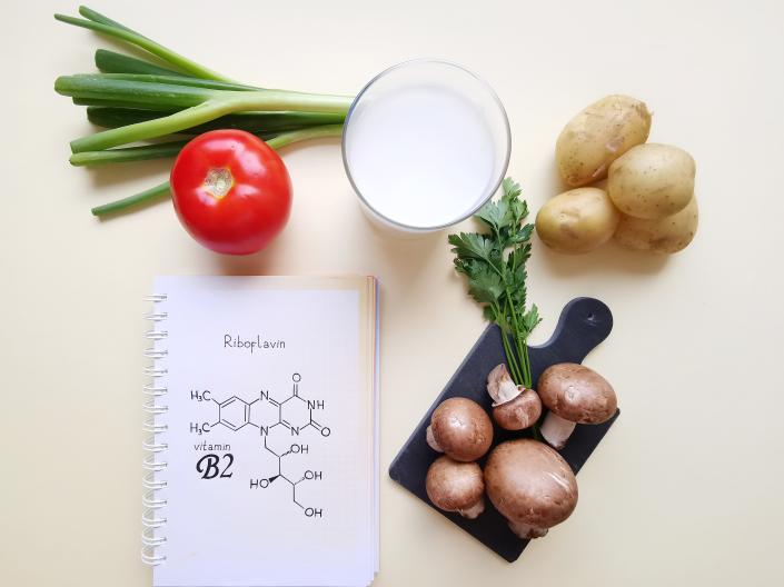 Assorted vegetables next to a notebook with chemical structures written down.
