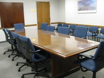 A conference room with a rectangular long table and blue chairs