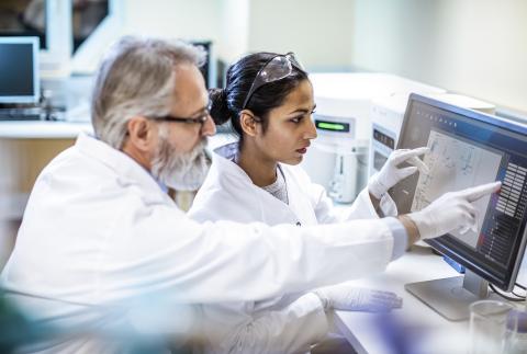 Two scientists collaborating to interpret data on a computer screen.
