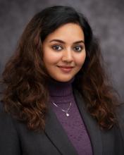 Headshot of Vidya Gopkumar in a purple sweater black blazer and grey blurred background