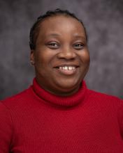 Headshot of Isioma Akwanamnye in a red sweater with a grey blurred background