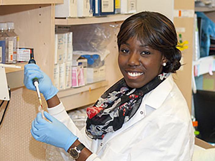 Female researcher in lab coat holding pipette