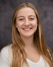 Headshot of Anellise Hutson in a white shirt with a gray blurred background