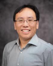 Headshot of Jack Su in a green collared button up with a grey blurred background