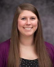 Headshot of Tawna Mangosh with a purple sweater and black polka dotted blouse and grey blurred background