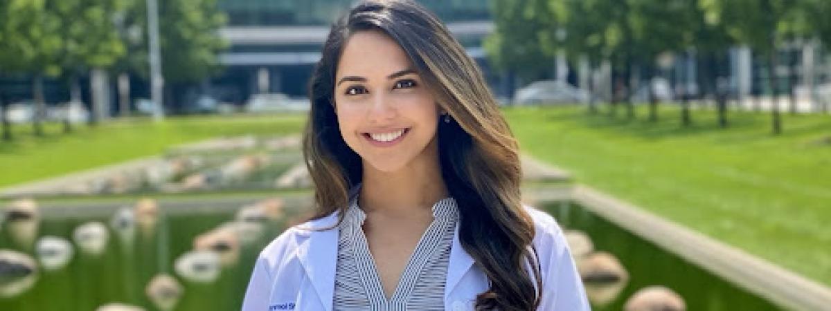 Anmol (Anna) Sharma in her whitecoat in front of a hospital building