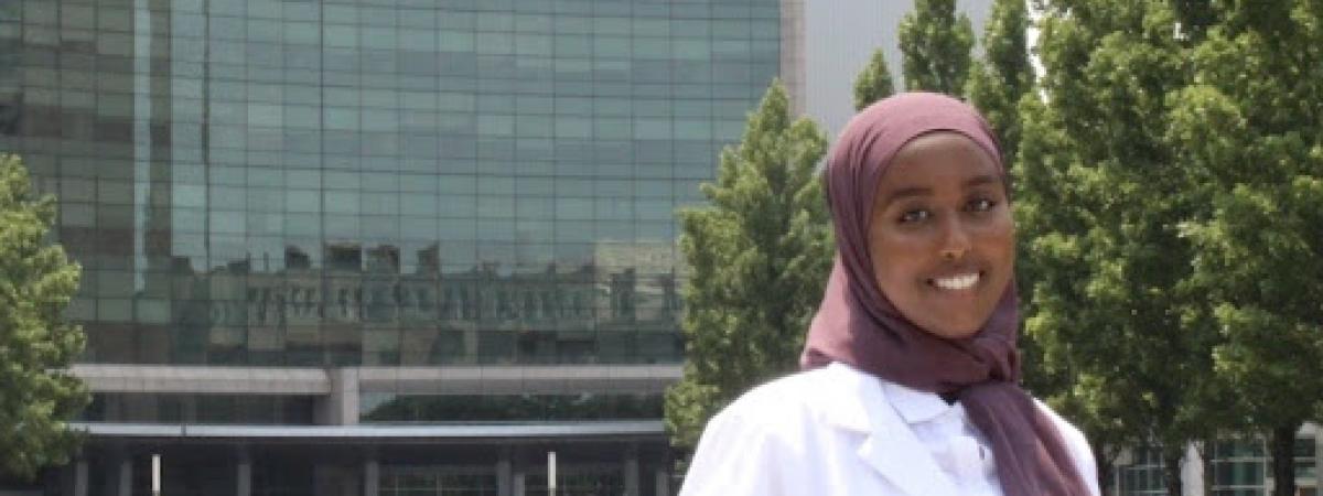 Asma Abukar in her whitecoat in front of a hospital 
